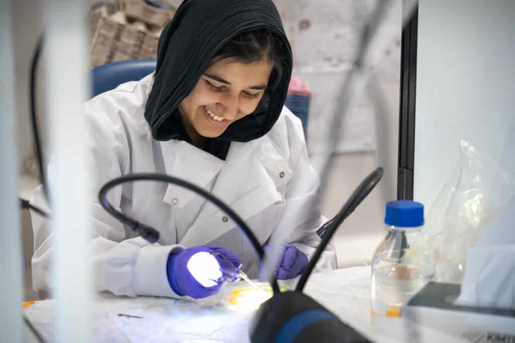 Smiling student working on plates at a lab bench.